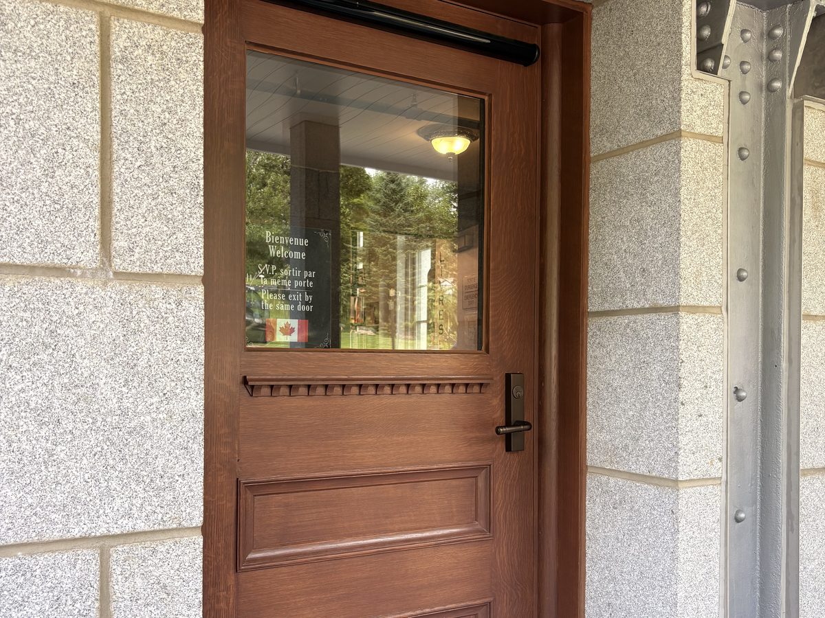 Opérateur de porte automatique installé au-dessus d’une porte de bois